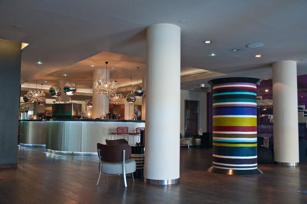 A modern hotel lobby and bar area with colorful lighting and design accents